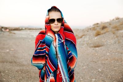 Woman with blanket standing at beach