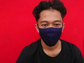 Portrait of teenage girl covering face against red wall