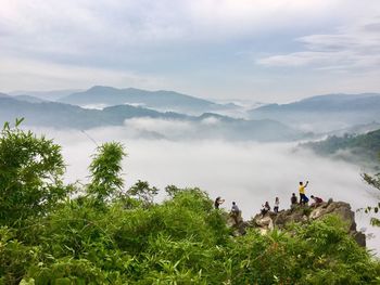 People on rock overlooking foggy mountains