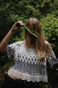 Midsection of woman standing against plants