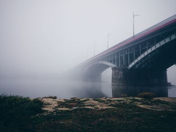 Bridge over river in foggy weather