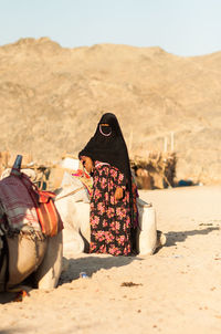 Rear view of woman sitting on sand