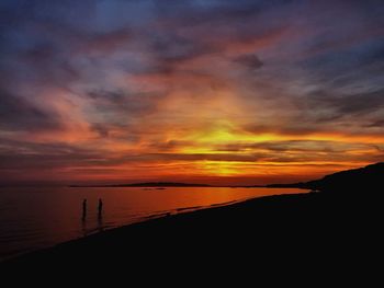 Scenic view of sea against dramatic sky during sunset