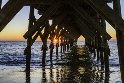 Pier over sea against sky during sunset