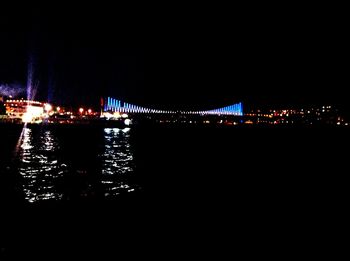 Illuminated bridge over river at night