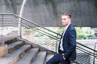 Smiling of young businessman walking on staircase