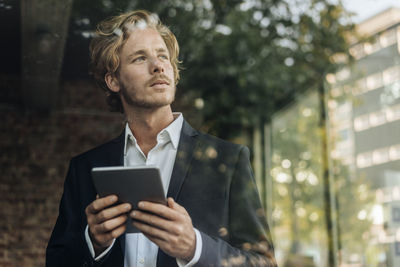 Businessman with tablet looking away