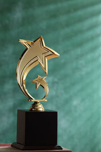 Close-up of trophy on table against green wall