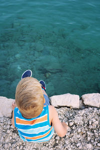 Rear view of boy sitting by sea