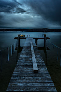 Wooden jetty over lake against sky at dusk