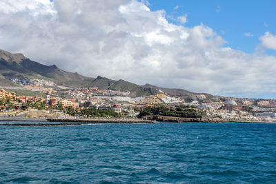 Scenic view of sea by town against sky