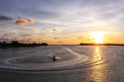 Jet boat sailing in sea against sky during sunset