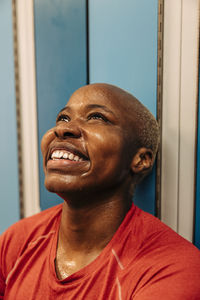 Happy female athlete looking up sitting in locker room
