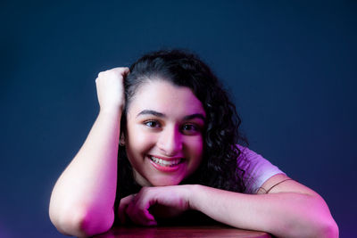 Portrait of young woman against blue background