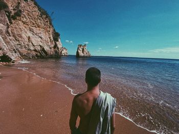 Rear view of man looking at sea shore. pinhão beach in algarve, portugal