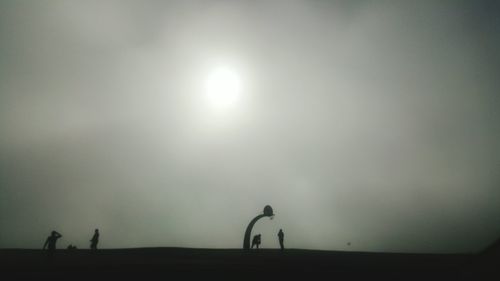 Silhouette men against moon in sky