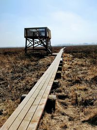 Abandoned railroad tracks on field against sky