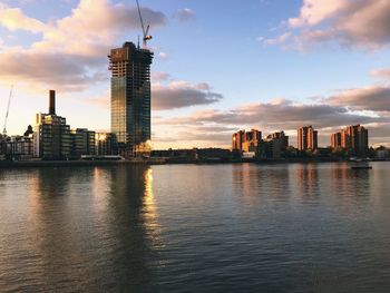 Scenic view of river by buildings against sky during sunset