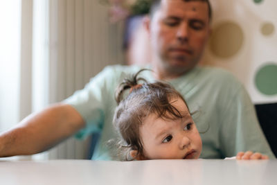 Portrait of a girl in her father's arms at the table.