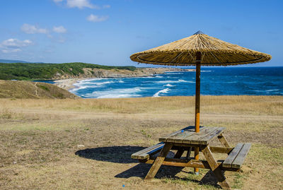 Deck chairs on beach against sky