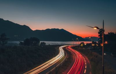 Light trails on street against sky at sunset