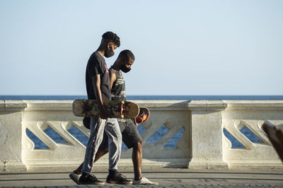 Rear view of people at sea shore against clear sky