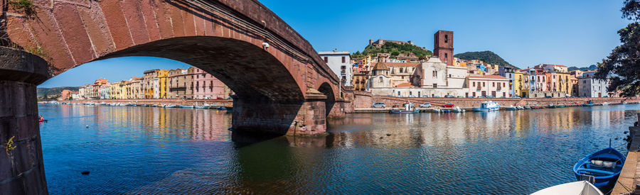 Bridge over canal by buildings in city against sky