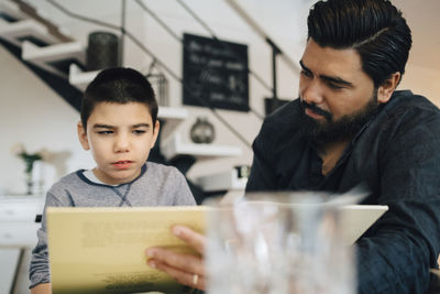 Father teaching autistic son while sitting in living room at home