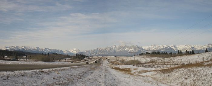 Road amidst snow covered landscape against sky