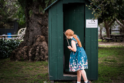 Young 9-11 year old red headed girl explores rustic dunny outhouse shed at a historic cottage.