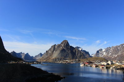 Scenic view of sea and mountains against blue sky