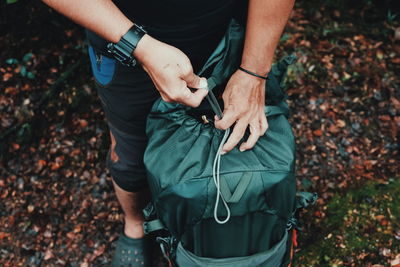 Low section of man with luggage in forest during autumn