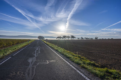 Road amidst field against sky