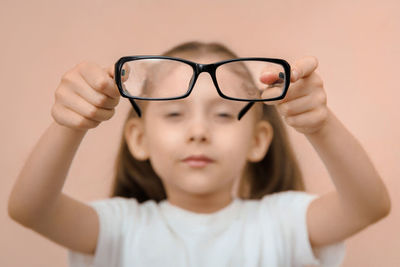 Portrait of young woman wearing sunglasses against white background