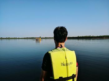 Rear view of man in lake against clear sky