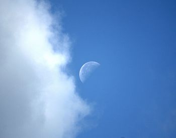 Low angle view of moon in blue sky