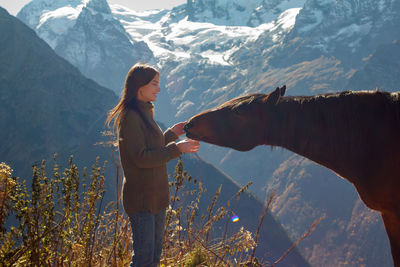Girl with a horse in the background of mountains