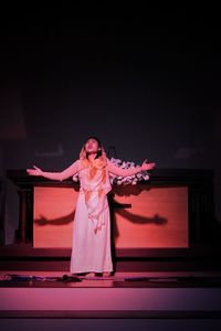 Woman with arms raised standing on stage