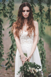 Beautiful young woman standing against plants