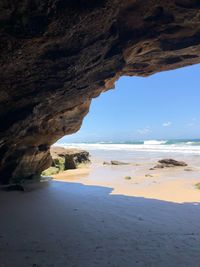 Rock formation on beach against sky