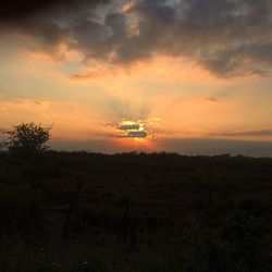 Scenic view of silhouette field against sky during sunset