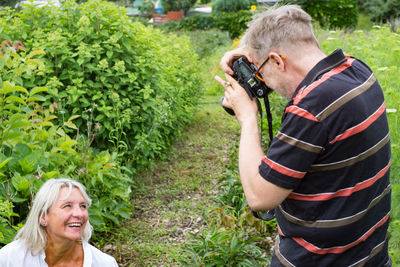 Friends photographing while standing by plants