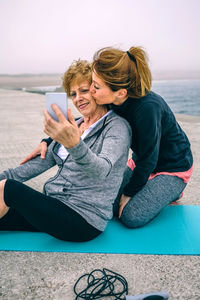 Young woman using phone while sitting on beach