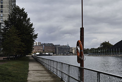 Bridge over river by buildings in city against sky