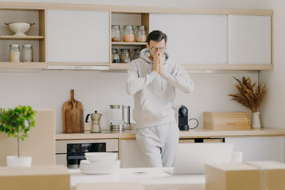 Stressed man looking at laptop while standing in kitchen