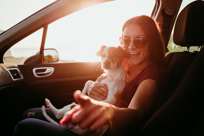 Portrait of smiling woman with dog sitting in car