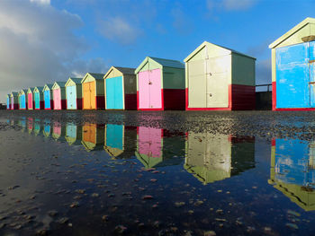 Multi colored huts on beach by buildings against sky