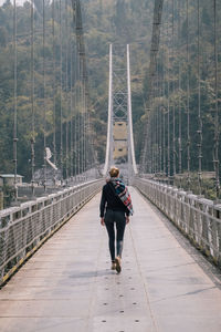 Rear view of man walking on footbridge