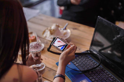 Woman using mobile phone while sitting on table