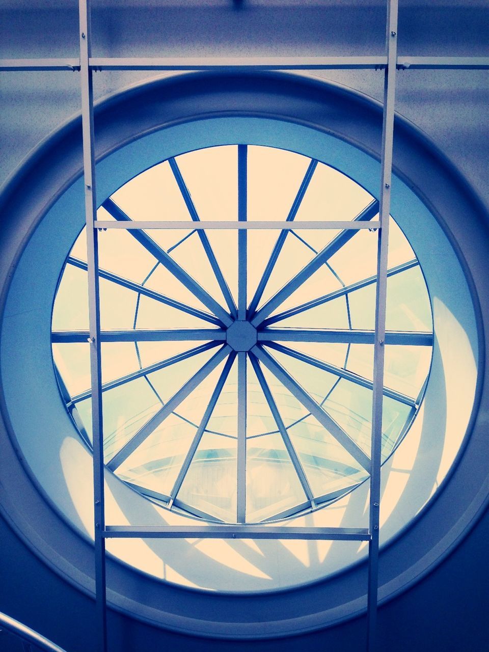 indoors, circle, geometric shape, architecture, built structure, low angle view, pattern, window, glass - material, skylight, directly below, shape, ceiling, design, transparent, architectural feature, no people, spiral staircase, metal, full frame